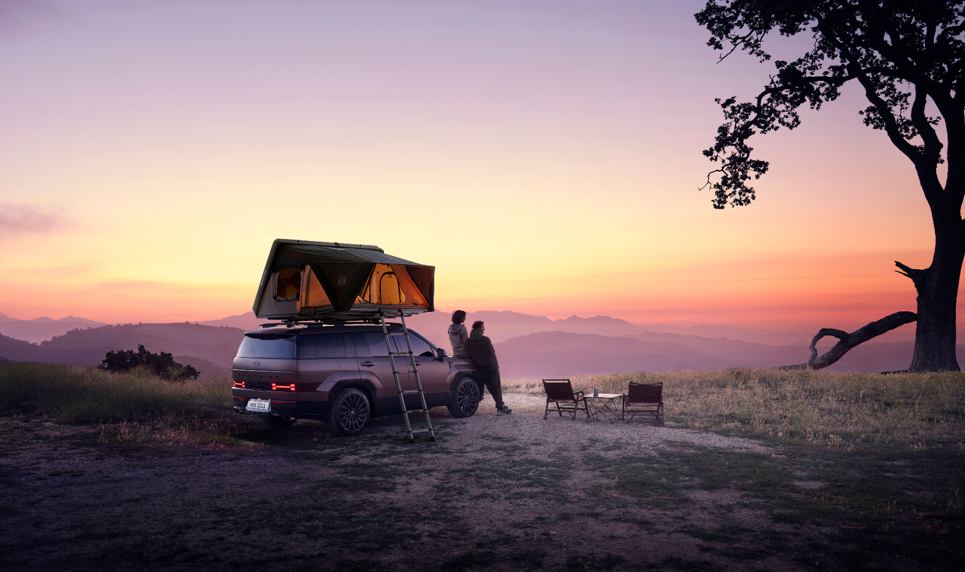 Couple in front of a rooftop tent at sunset